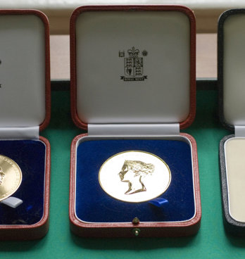 Three Society medals displayed in wooden boxes.