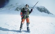 Man in winter gear ascending a snow covered mountain.
