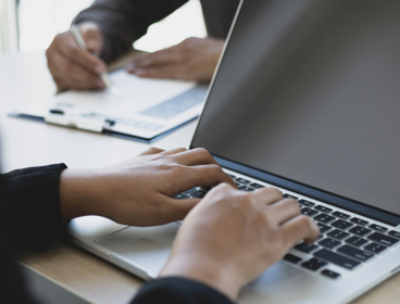Two hands typing on laptop keyboard.