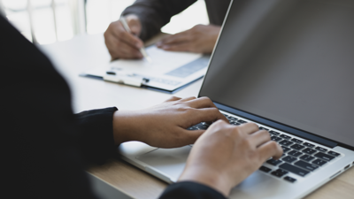 Two hands typing on laptop keyboard.