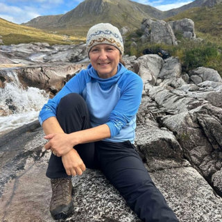 Lisa Drewe sitting on rocky ground.