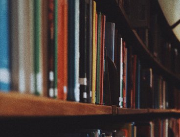 Books stacked on a wooden shelf.