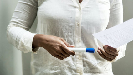 Close-up of a person holding a piece of paper and pen.