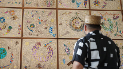Hormazd Narwiella as seen from behind, standing in front of his mural at the Society and viewing it.