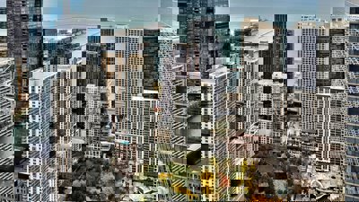 Cityscape with a park surrounded by high rise moder buildings. The buildings are lined by a sea. 