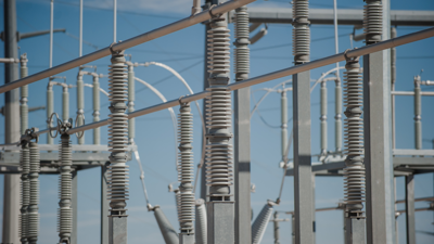 Grey metal power sation infresturucture stands before a clear blue sky background.