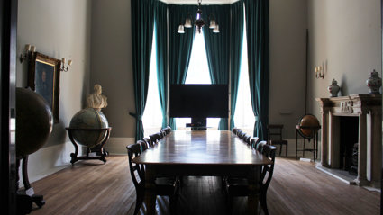 Stately looking meeting room with a large wooden table and several globes.