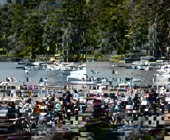 A view of Bowness with tourists and bpats on the lake