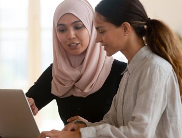 Two people working on laptop.