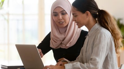 Two people working on laptop.