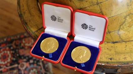 Two royal medals sitting on a floor globe.
