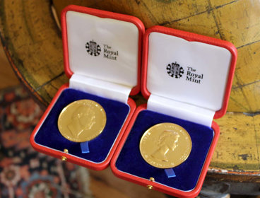 Two royal medals sitting on a floor globe.