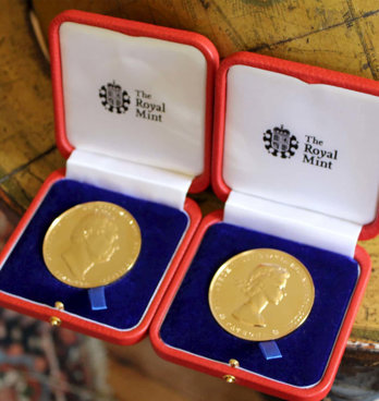 Two royal medals sitting on a floor globe.