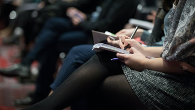 Woman holding a pen and notebook while attending a lecture..