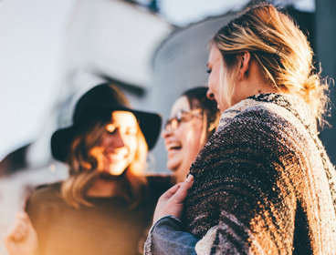 Three people outside laughing.