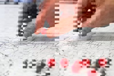 Person holding a round red pin and placing it on a map