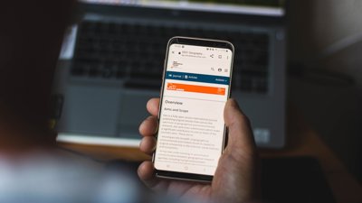 Hand holding mobile phone with Geo home page on screen