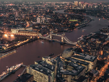 Aerial view of the City of London and Tower Bridge illuminated at night time.