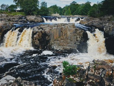 Fast flowing river with waterfalls falling over a rocky ledge.