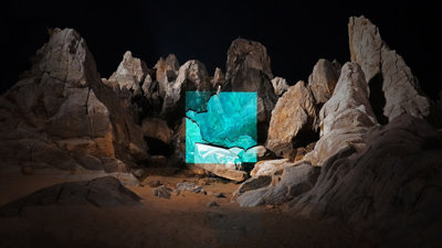 A red rock formation at night with a blue square projected on to it. Photograph titled 'Chuam Rock 2021'.