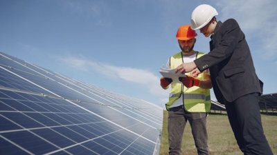 Two people working next to solar panels.