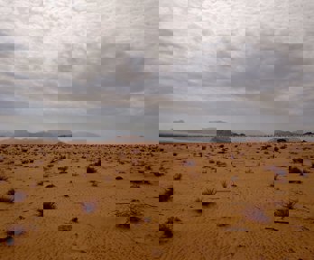 Brown sand under white clouds