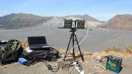 Laptop and UV monitoring equipment in mountainous landscape.