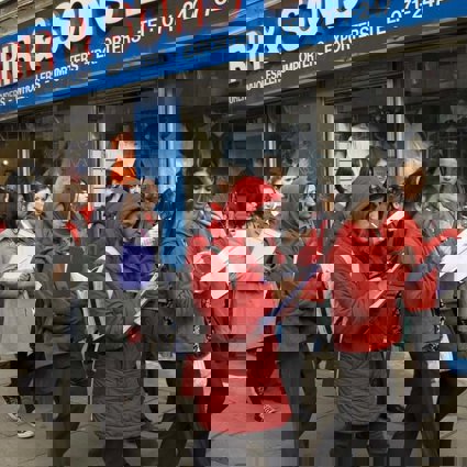 A group of female students with clipboards are walking down a high street taking notes of what they can see for their Geography fieldwork