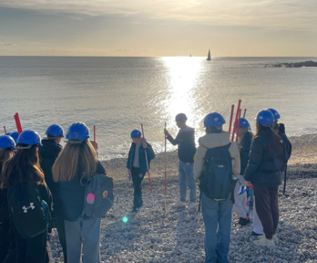 Teacher and students conducting geographical fieldwork on the beach.