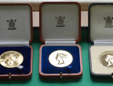 Three Society medals displayed in wooden boxes.