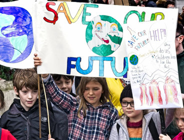 A group of children holding up climate advocacy posters reading 'save our future'.