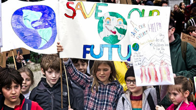 A group of children holding up climate advocacy posters reading 'save our future'.