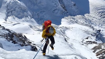 Person climbing up Mount Everest in snow.