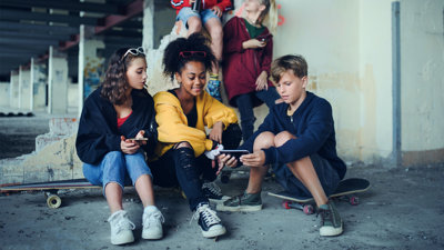 A group of teenagers sitting with handheld devices.