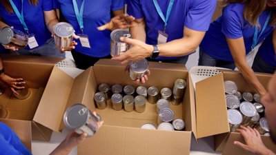 People filling donations box with tin cans.