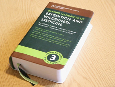 A copy of the Oxford Handbook of Expedition and Wilderness Medicine on a desk.