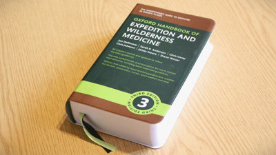 A copy of the Oxford Handbook of Expedition and Wilderness Medicine on a desk.