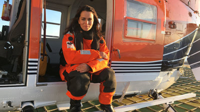 Esther Horvath sitting on the edge of a helicopter.