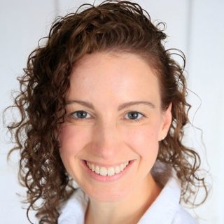 Person with curly brown hair smiling.