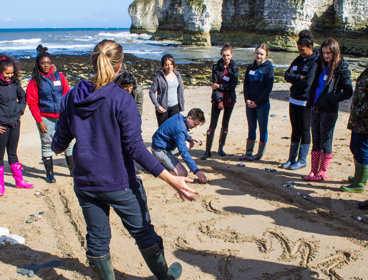 A group of students on a training course. They are standing on a beach.