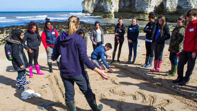 A group of students on a training course. They are standing on a beach.
