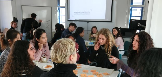 A group of people having a discussion around a table of post-it notes