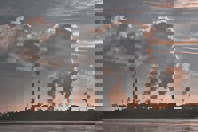 An industrial scene with smoke billowing out of tall chimneys