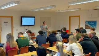 Chloë Searl in front of a classroom full of students.