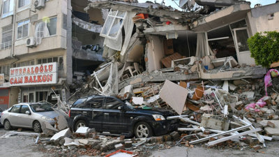 Cars in front of destroyed building post-earthquake. 