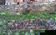 Traditional ceramic figures lined up in the grass against a stone wall.