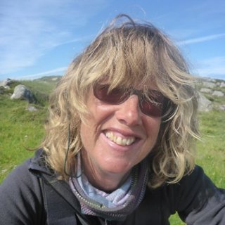 Person wearing sunglasses smiling against natural backdrop.