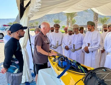 People talking in Oman next to yellow kayak.