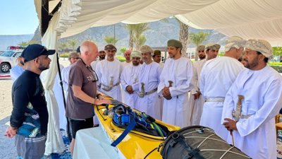 People talking in Oman next to yellow kayak.