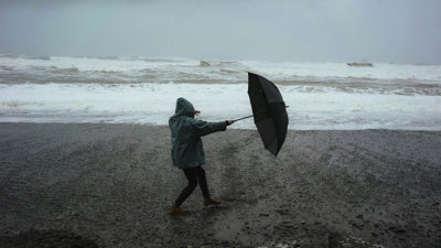 erson Holding Umbrella On Windy Beach